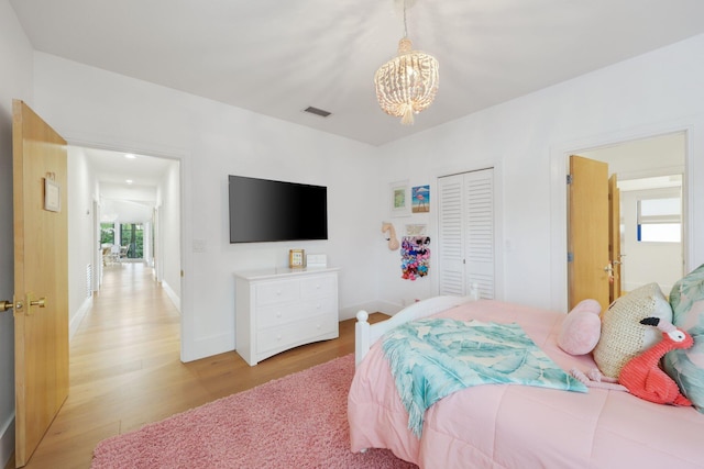 bedroom with a closet, an inviting chandelier, and light hardwood / wood-style flooring