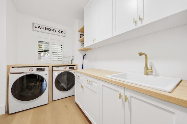 clothes washing area featuring cabinets, light wood-type flooring, sink, and washing machine and clothes dryer