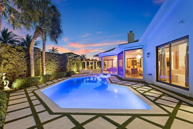 pool at dusk featuring a patio area