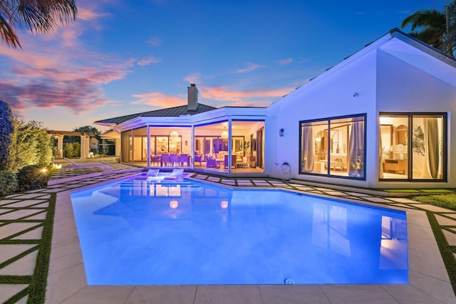 pool at dusk featuring a patio