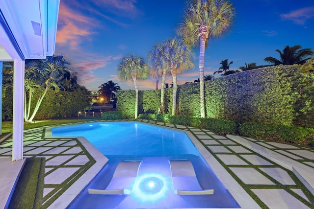 pool at dusk with a patio area