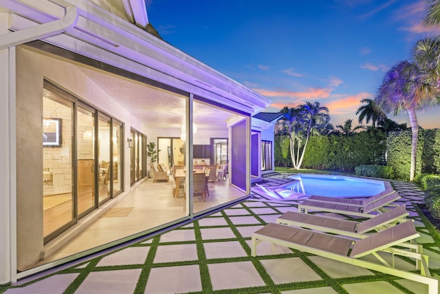 pool at dusk featuring a patio