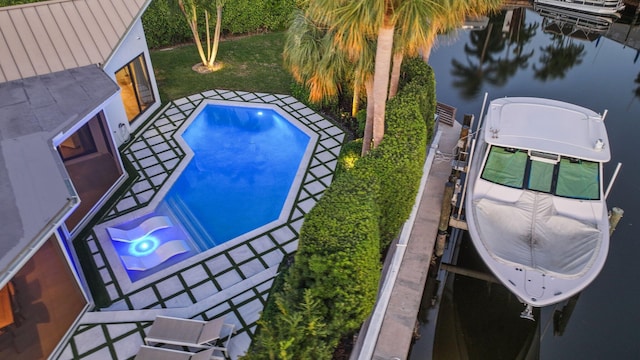 view of swimming pool featuring a yard, a boat dock, and a water view