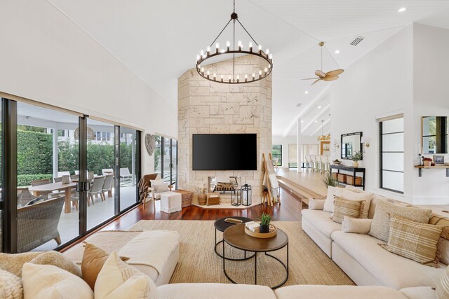 living room with hardwood / wood-style flooring, ceiling fan with notable chandelier, and high vaulted ceiling