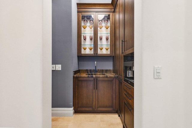 bar with dark brown cabinetry and sink