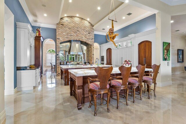 dining room featuring decorative columns, ornamental molding, a tray ceiling, a notable chandelier, and a high ceiling