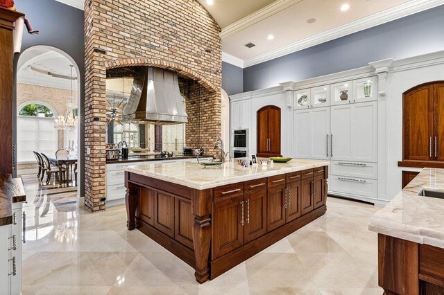 kitchen with a kitchen island, ornamental molding, a high ceiling, and an inviting chandelier