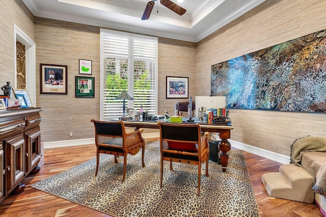 home office with ceiling fan, wood finished floors, baseboards, ornamental molding, and a raised ceiling