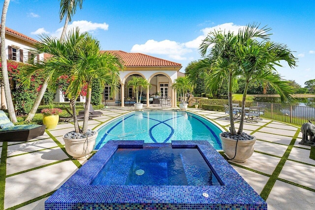 view of swimming pool with a patio, fence, and a pool with connected hot tub