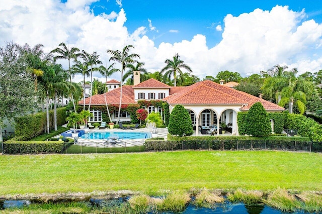 rear view of house featuring a yard and a fenced in pool