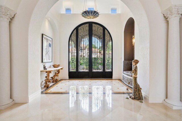 foyer entrance featuring french doors, ornate columns, and a high ceiling