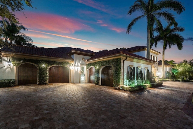 mediterranean / spanish-style home with decorative driveway, an attached garage, and stucco siding