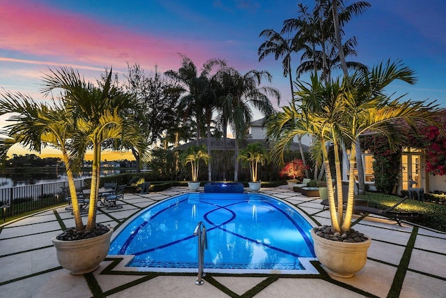 pool at dusk featuring a fenced in pool, a water view, a patio, and fence