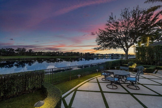 patio terrace at dusk with a water view and fence