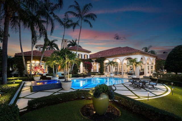 pool at dusk featuring a patio area