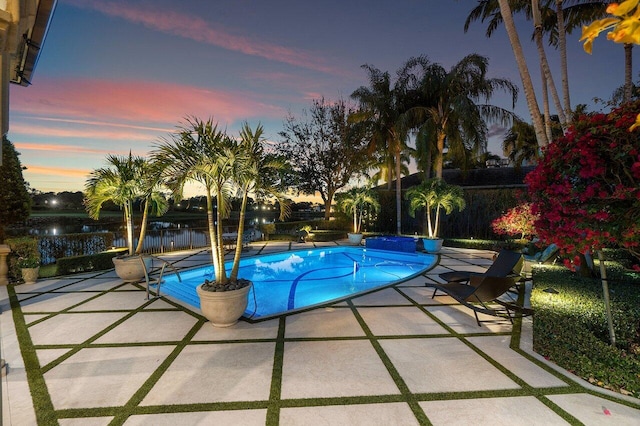 pool at dusk with a fenced in pool, a water view, a patio, and fence