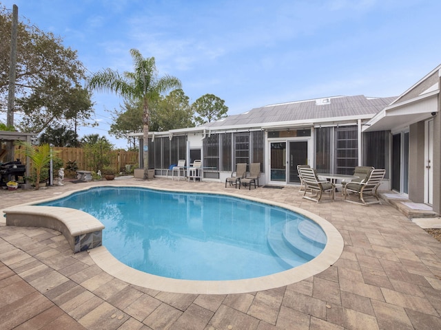 view of swimming pool with a sunroom and a patio