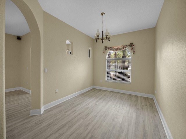 empty room featuring light hardwood / wood-style floors and an inviting chandelier