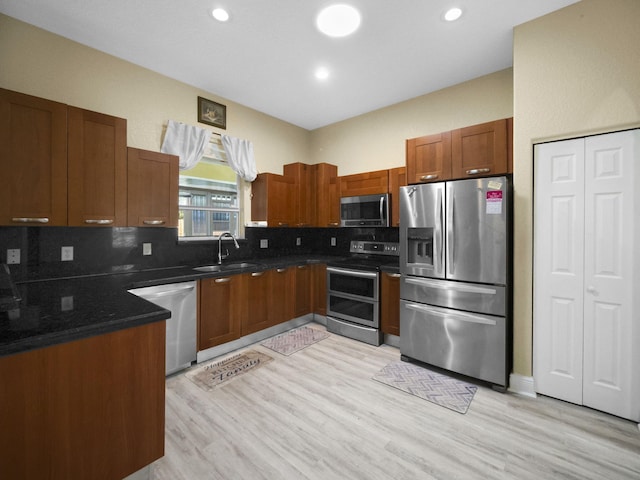 kitchen featuring appliances with stainless steel finishes, tasteful backsplash, light hardwood / wood-style flooring, and sink