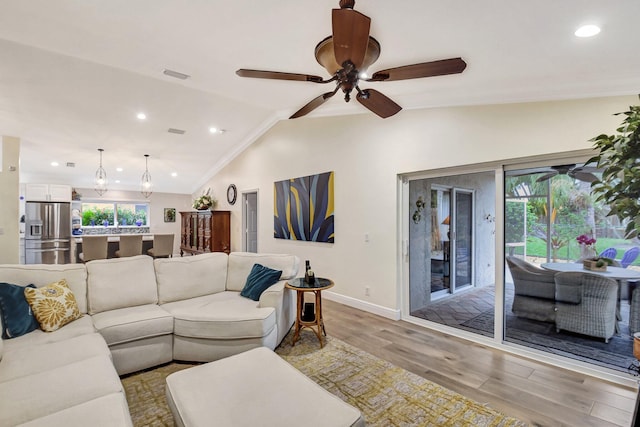 living room featuring ceiling fan, light hardwood / wood-style flooring, and vaulted ceiling