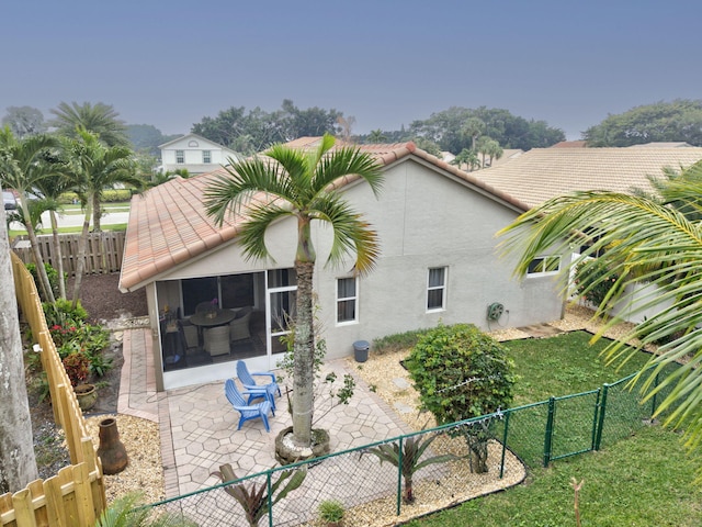 back of property with a lawn, a patio area, and a sunroom