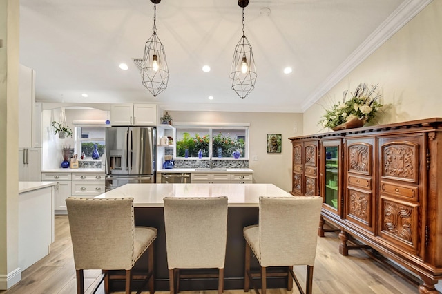 kitchen featuring decorative light fixtures, light hardwood / wood-style floors, white cabinetry, and stainless steel appliances