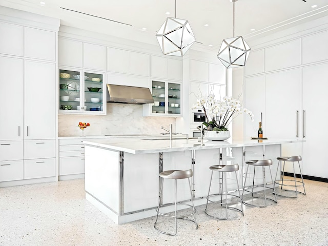 kitchen with white cabinetry, cooktop, a large island with sink, pendant lighting, and extractor fan