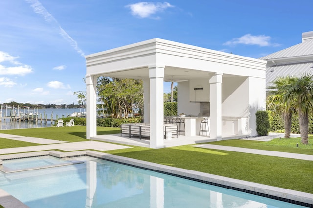 view of swimming pool with a bar, a yard, a water view, and a patio