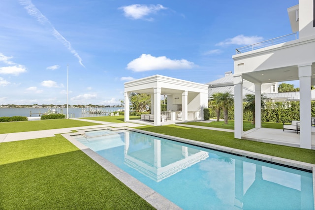 view of pool with a lawn, a patio area, a water view, and a bar