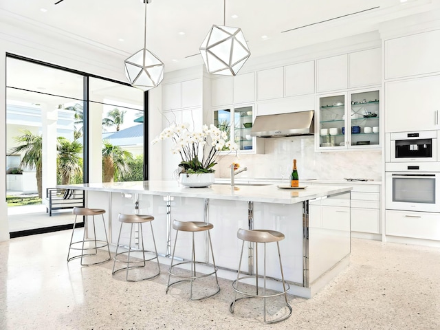 kitchen with hanging light fixtures, white cabinetry, extractor fan, and plenty of natural light