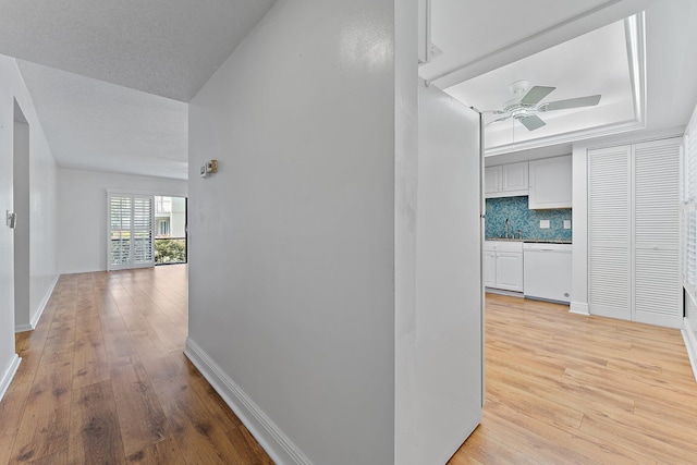 corridor featuring a textured ceiling and light hardwood / wood-style floors