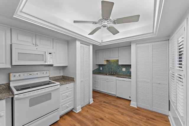 kitchen featuring white appliances, white cabinetry, a raised ceiling, and sink