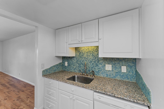 kitchen with dishwasher, sink, hardwood / wood-style floors, dark stone counters, and white cabinets