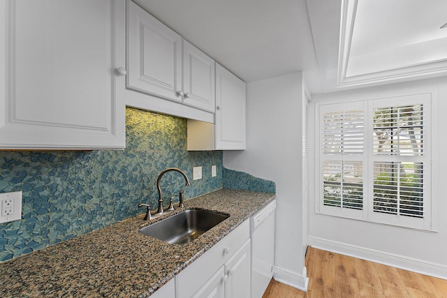 kitchen with white cabinetry, sink, dishwasher, backsplash, and dark stone countertops