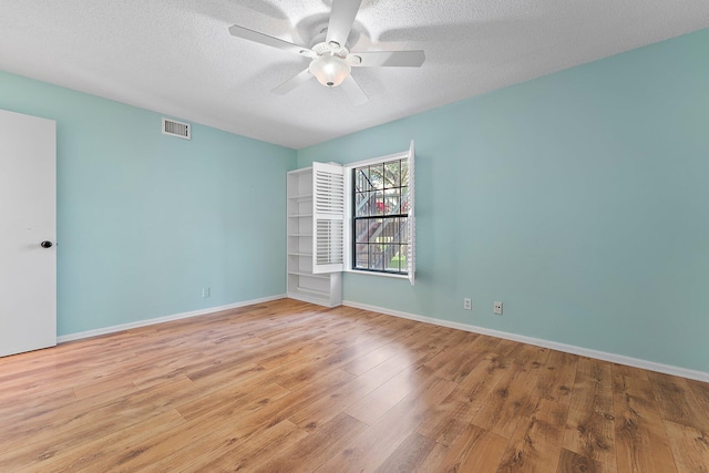 empty room with a textured ceiling, light wood-type flooring, and ceiling fan