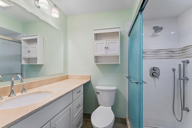 bathroom with a tile shower, vanity, and toilet