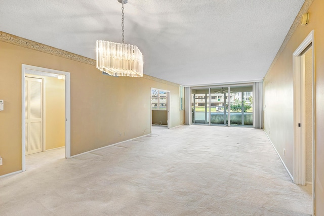 carpeted spare room featuring a textured ceiling and a notable chandelier