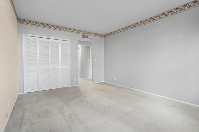 unfurnished bedroom featuring a textured ceiling, light carpet, and a closet