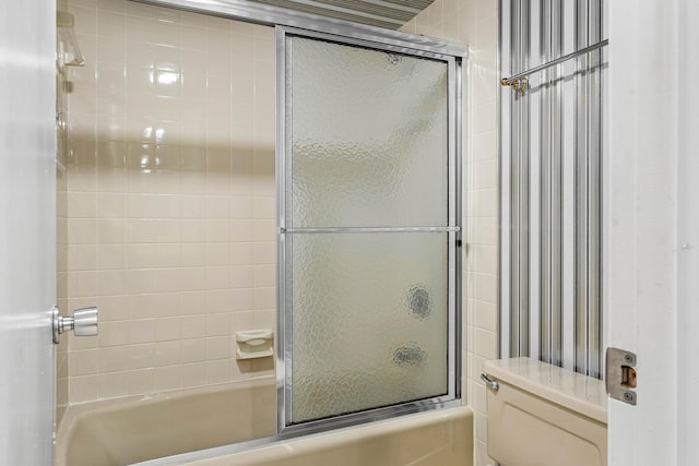 bathroom with toilet and bath / shower combo with glass door