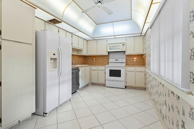 kitchen with cream cabinetry, decorative backsplash, white appliances, and sink