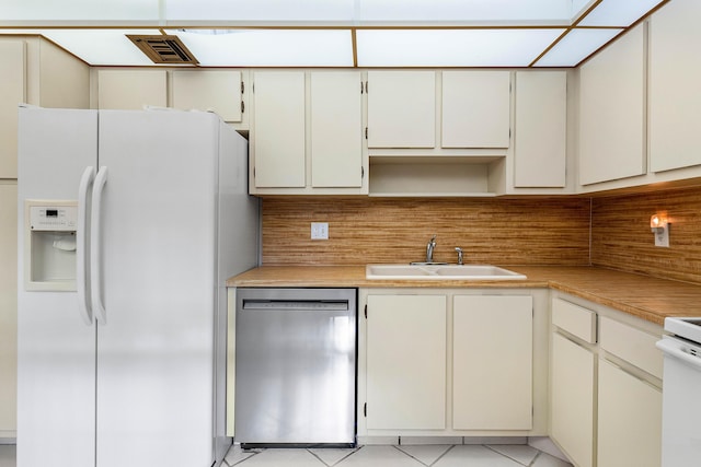 kitchen with white fridge with ice dispenser, sink, tasteful backsplash, stainless steel dishwasher, and light tile patterned floors