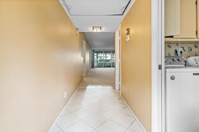 hallway with separate washer and dryer and light tile patterned floors