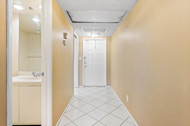 hallway with sink, light tile patterned flooring, and a textured ceiling