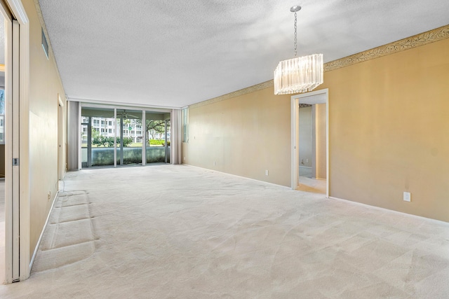 spare room with floor to ceiling windows, light carpet, a textured ceiling, and a notable chandelier