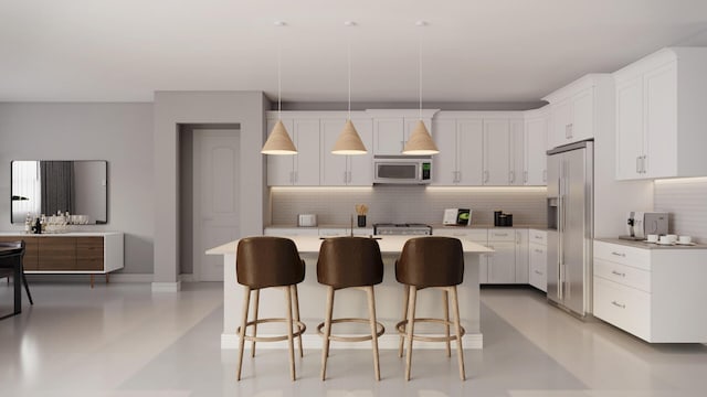 kitchen featuring stainless steel appliances, an island with sink, pendant lighting, decorative backsplash, and white cabinets