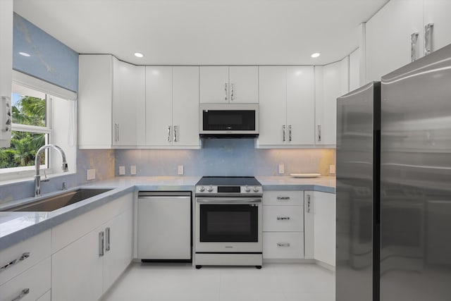 kitchen with backsplash, sink, white cabinets, and appliances with stainless steel finishes