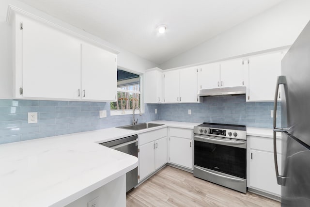 kitchen with appliances with stainless steel finishes, white cabinetry, lofted ceiling, and sink