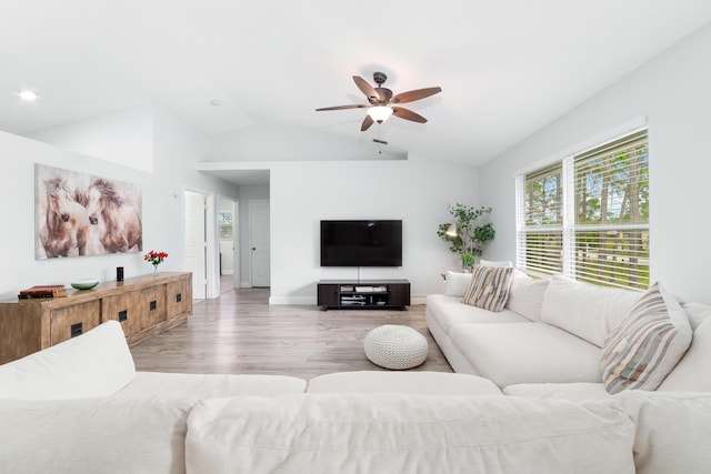 living room with ceiling fan, light hardwood / wood-style floors, and vaulted ceiling