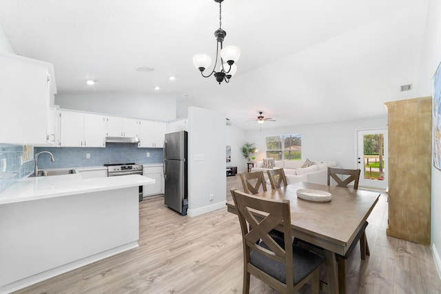 dining room with ceiling fan with notable chandelier, light wood-type flooring, lofted ceiling, and sink