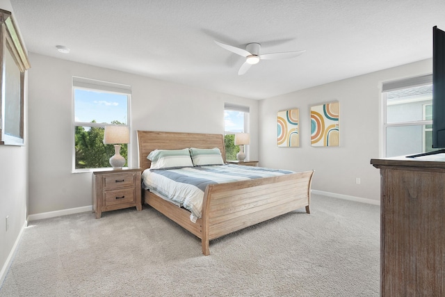 bedroom with light carpet, a textured ceiling, multiple windows, and ceiling fan